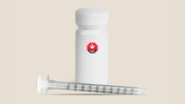 Flacon d’huile de cannabis accompagné d’une seringue de dosage graduée.