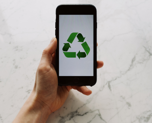 Main tenant un téléphone affichant le symbole de recyclage, illustrant l’engagement de la SQDC envers le recyclage et les pratiques écoresponsables