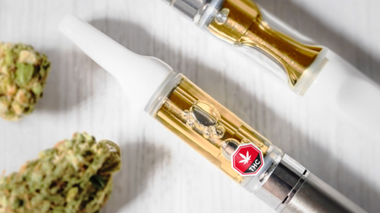 510-thread weed vape cartridge with a THC symbol, placed near dried flower.